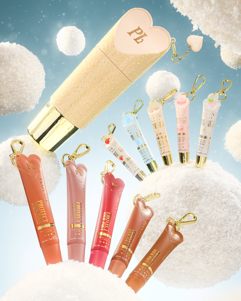 Un set di tubi portachiavi per balsamo per labbra a forma di cuore con portachiavi dorati, visualizzati su uno sfondo stravagante di soffici nuvole bianche e un cielo azzurro. Il set include un grande tubo glitter dorato con un cappuccio a forma di cuore rosa, diversi tubi più piccoli di lucidalabbra o crema in tonalità pesca, rosa, rosso e marrone e portachiavi più piccoli blu pastello e rosa.