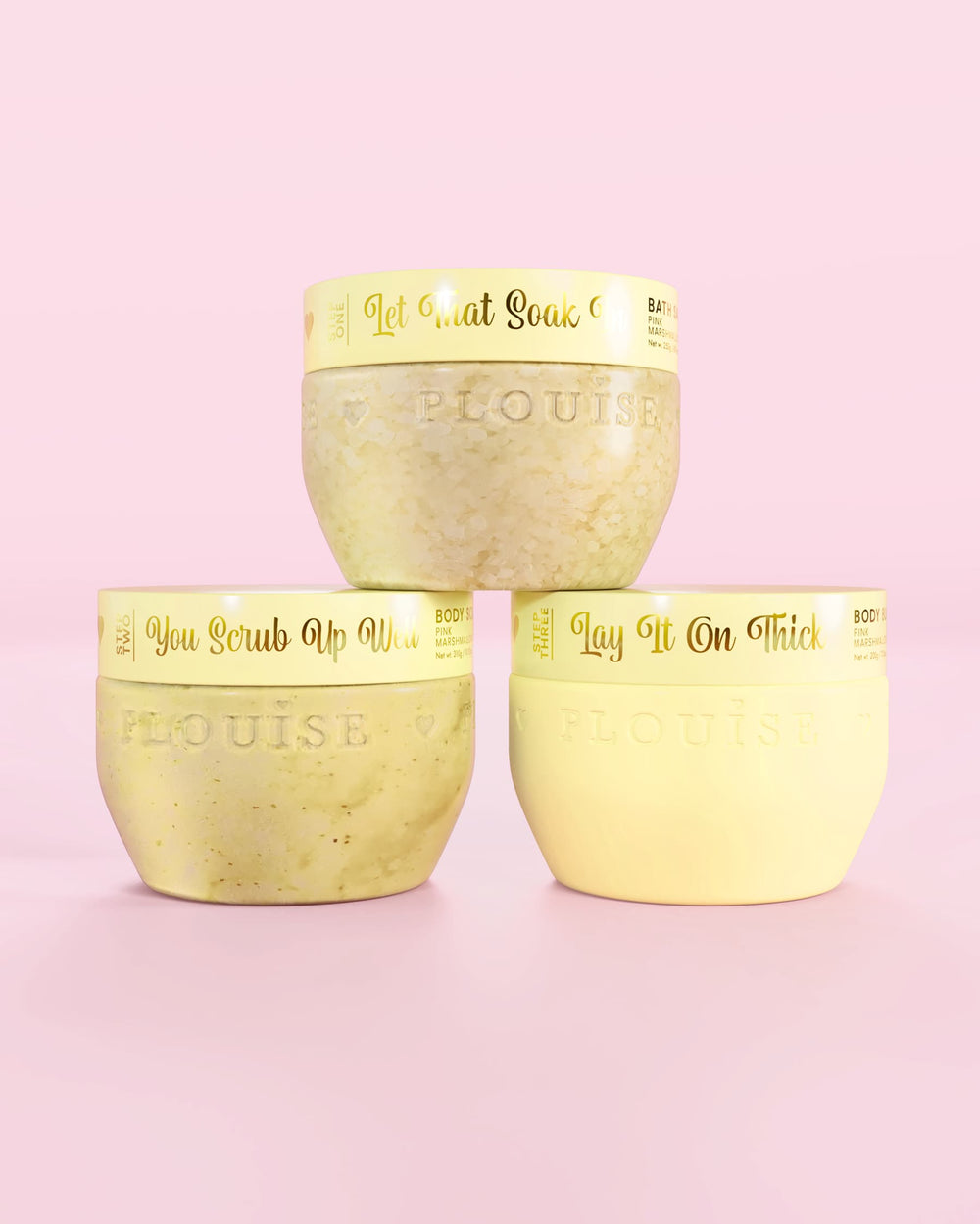 Tre contenitori gialli P.Louise Hop Into Self-Care Starwberry Shortcake con sali da bagno, scrub corpo e burro per il corpo con testo dorato su sfondo rosa