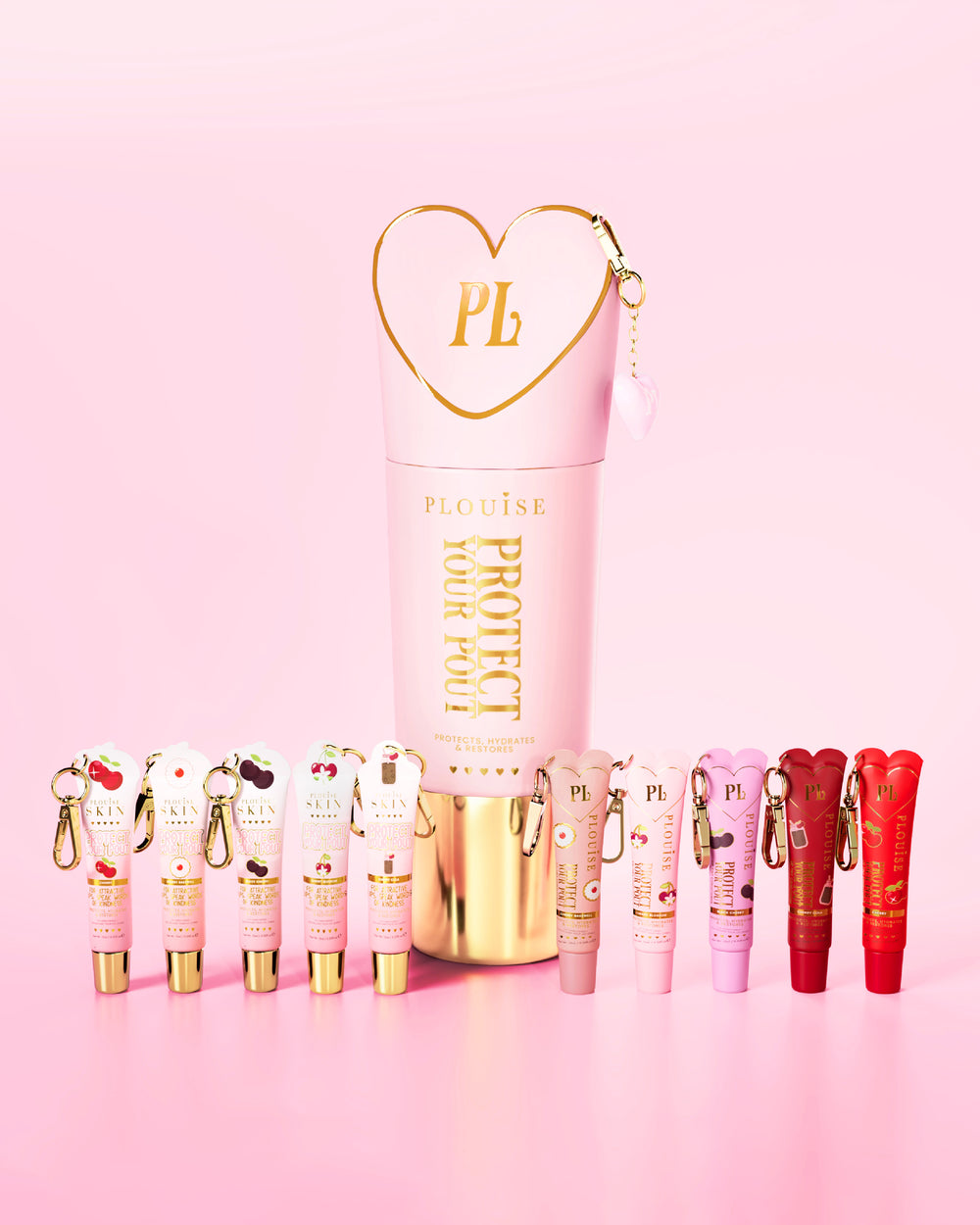 Set di balsami per labbra rosa e rossi al profumo di ciliegia con un prominente rosa e oro che proteggono la tua bottiglia di brocca al centro su uno sfondo rosa.