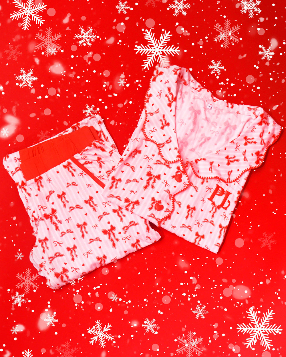 Paio di pigiami a righe bianche e rosa con disegni di fiocchi rossi festivi su sfondo rosso con fiocchi di neve