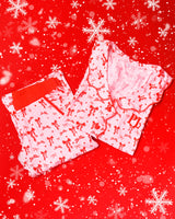 Paio di pigiami a righe bianche e rosa con disegni di fiocchi rossi festivi su sfondo rosso con fiocchi di neve