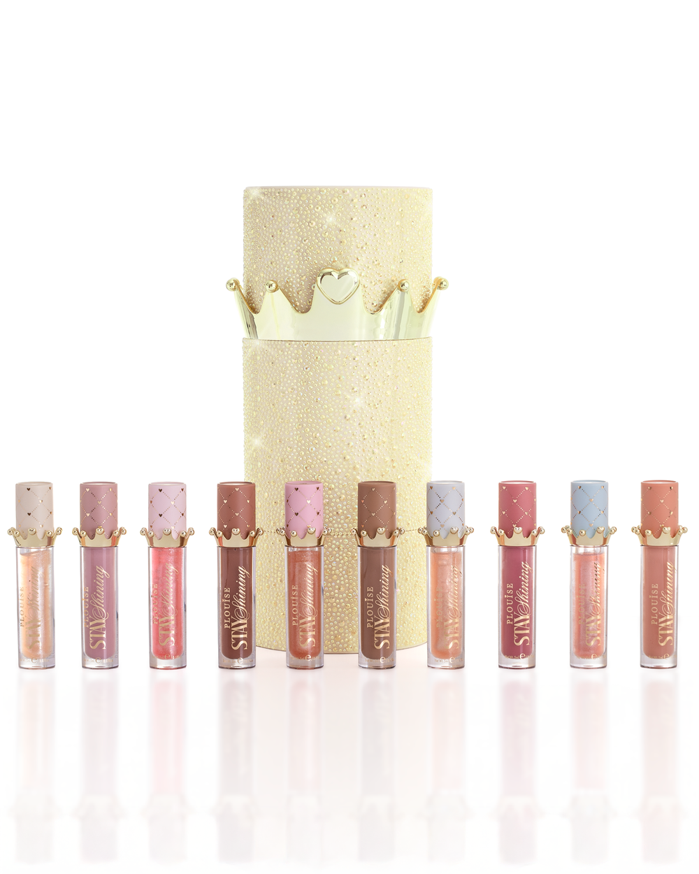 Un set di dieci prodotti P.Louise Christmas Stay Shining Lip Oil disposti in fila davanti a una scatola cilindrica color oro scintillante con un coperchio dorato a corona, su uno sfondo bianco pulito.