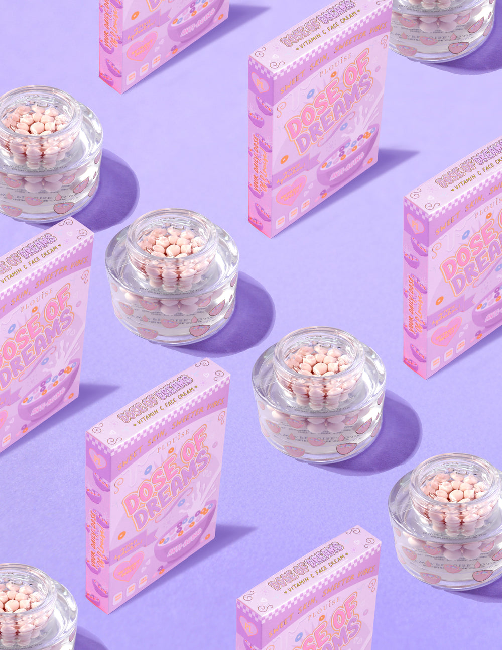 Contenitori trasparenti di P.Louise DOse of Dreams Viatmin C Capsule Face Cream con capsule rosa al loro interno circondate da scatole di cereali rosa su sfondo viola