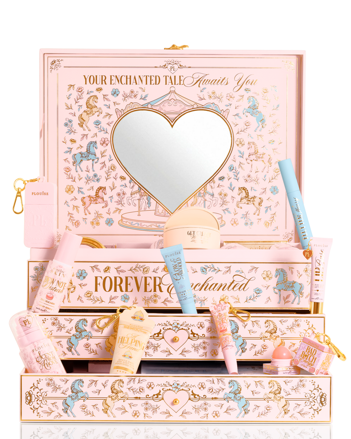 Un set regalo di bellezza PR di Natale rosa pastello, blu e giallo di P.Louise etichettato "La tua storia incantata" con uno specchio a forma di cuore sul coperchio e cassetti aperti, circondato da tubi cosmetici assortiti, flaconi e una piccola custodia su uno sfondo bianco.