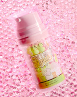 Una bottiglia di P.Louise Here I Glow Again Recovery Mask al profumo di orsetti di caramella con un'etichetta rosa e verde, con illustrazioni di orsetti di caramella, posizionati su uno sfondo rosa glitterato.