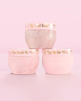 Tre contenitori rosa Marshmallow Hop Into Self-Care Pink di P.Louise con sali da bagno, scrub corpo e burro per il corpo con testo dorato su sfondo rosa