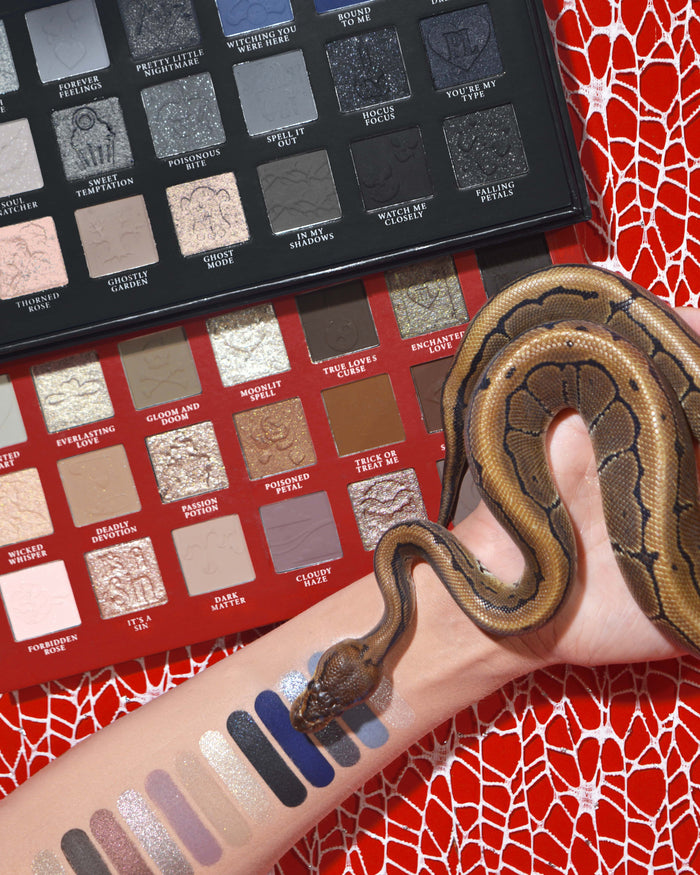 Palette di ombretti e trucco P.Louise Mystic Moonlight per Halloween con campioni su un braccio avvolto da un serpente su uno sfondo di ragnatela rossa