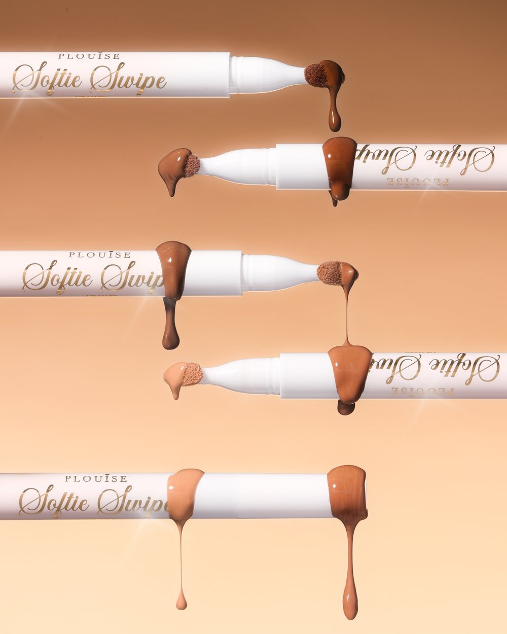 Un'immagine di cinque maschere per labbra colorate P.Louise Softie Swipe con il prodotto che cola dalle punte e che mostra le varie tonalità su uno sfondo beige