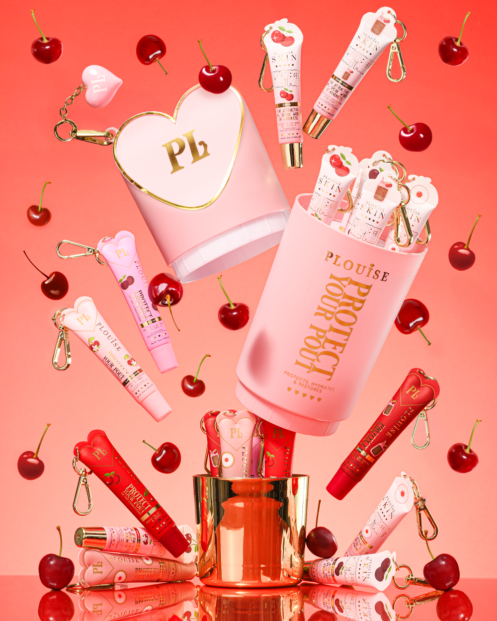 Set regalo Pink XL Protect Your Pout che si apre circondato da ciliegie e balsami per labbra rosa e rossi su sfondo rosa