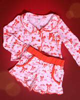 Set di pigiami natalizi per bambini a righe rosa e bianche con disegni di fiocchi rossi su uno sfondo rosso