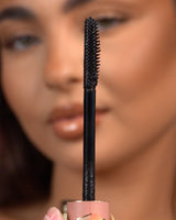Primo piano di un mascara waterproof P.Louise Tearproof tenuto davanti a un viso sfocato