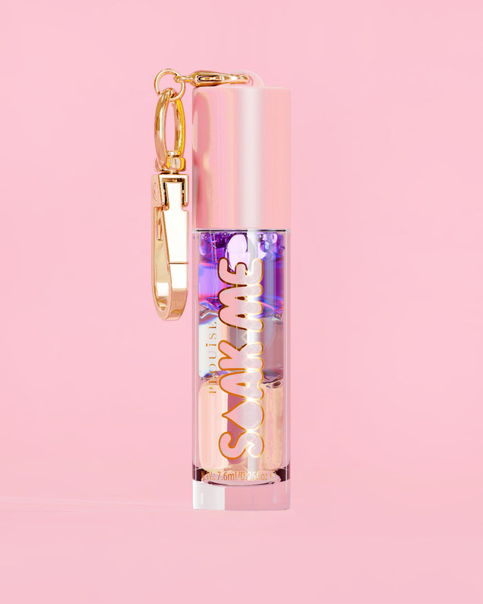 P. Louise Soak Me Lip Oil con strati di olio colorato in un tubo rosa con chiusura dorata su sfondo rosa