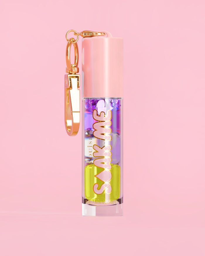 P. Louise Soak Me Lip Oil con strati di olio colorato in un tubo rosa con chiusura dorata su sfondo rosa
