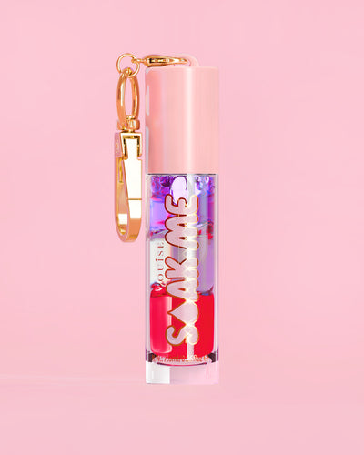 P. Louise Soak Me Lip Oil con strati di olio colorato in un tubo rosa con chiusura dorata su sfondo rosa