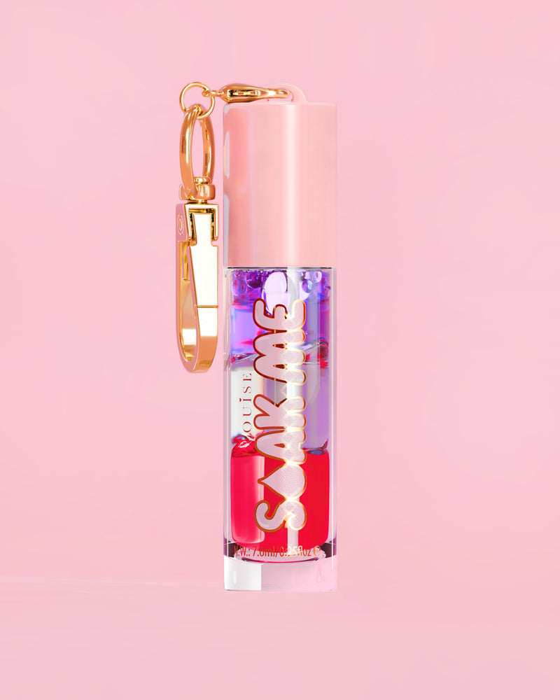 P. Louise Soak Me Lip Oil con strati di olio colorato in un tubo rosa con chiusura dorata su sfondo rosa