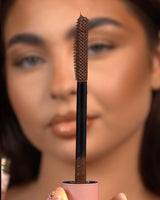 Primo piano di un mascara waterproof P.Louise Tearproof tenuto davanti a un viso sfocato