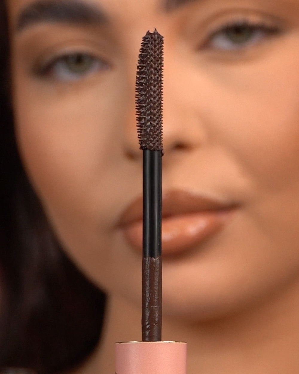 Primo piano di un mascara waterproof P.Louise Tearproof tenuto davanti a un viso sfocato