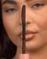 Primo piano di un mascara waterproof P.Louise Tearproof tenuto davanti a un viso sfocato
